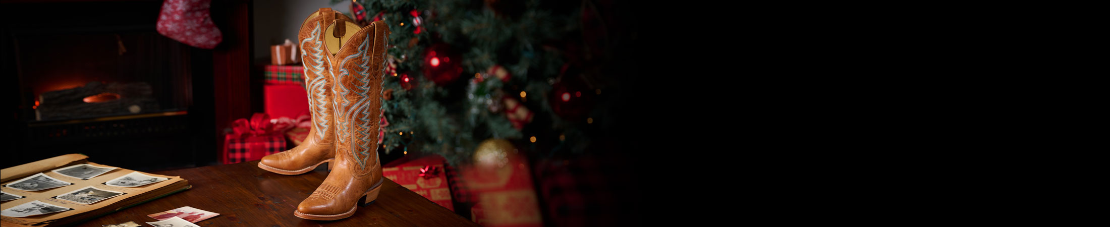 Evelyn 15” Western boot in brown posed on a wood table with a Christmas scene behind it.